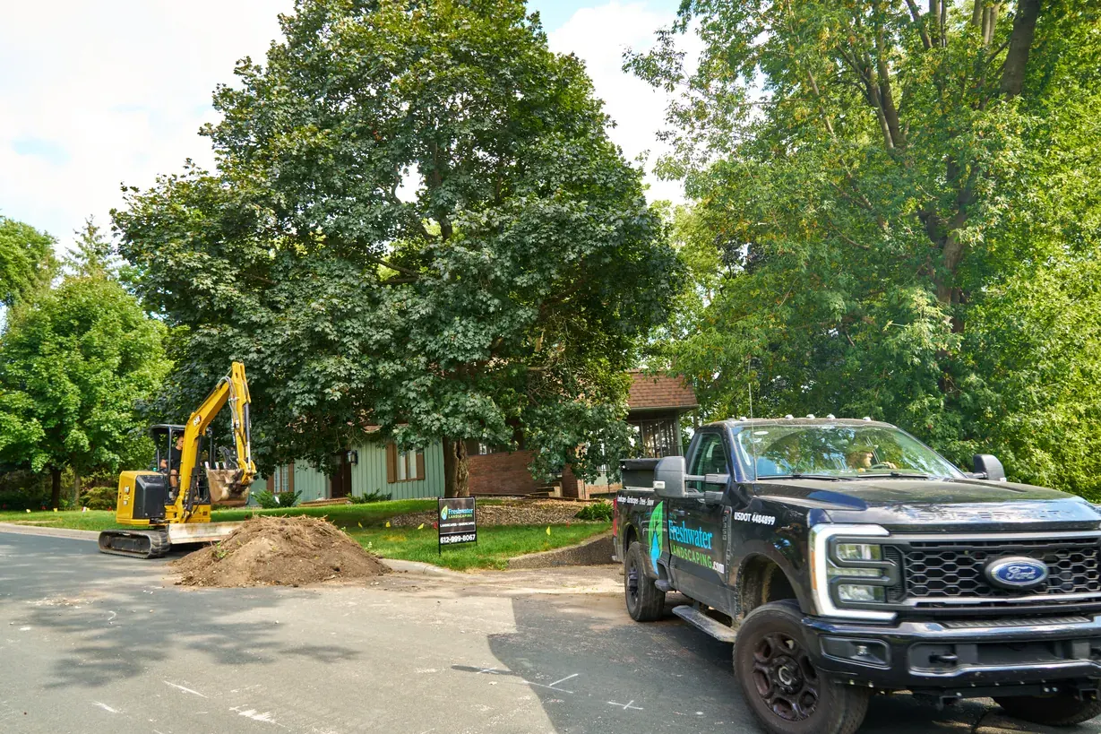 Freshwater excavator and truck at a street-side dig in Excelsior