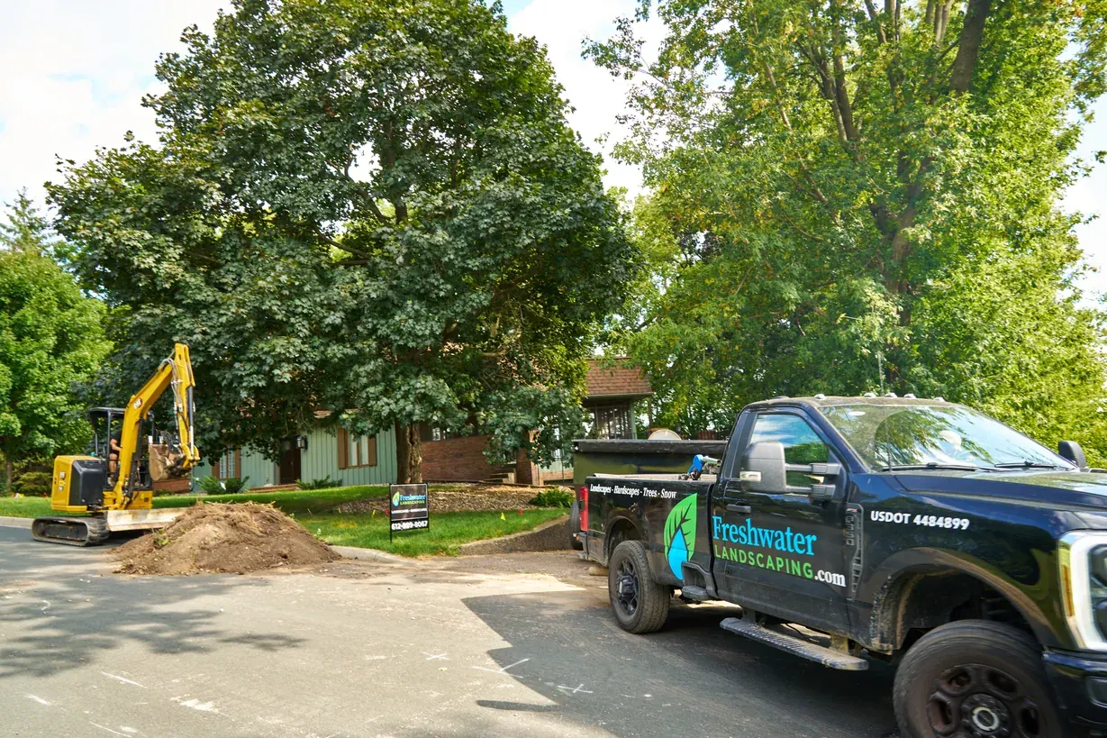 Freshwater Landscaping truck parked beside an excavator at a street-side dig