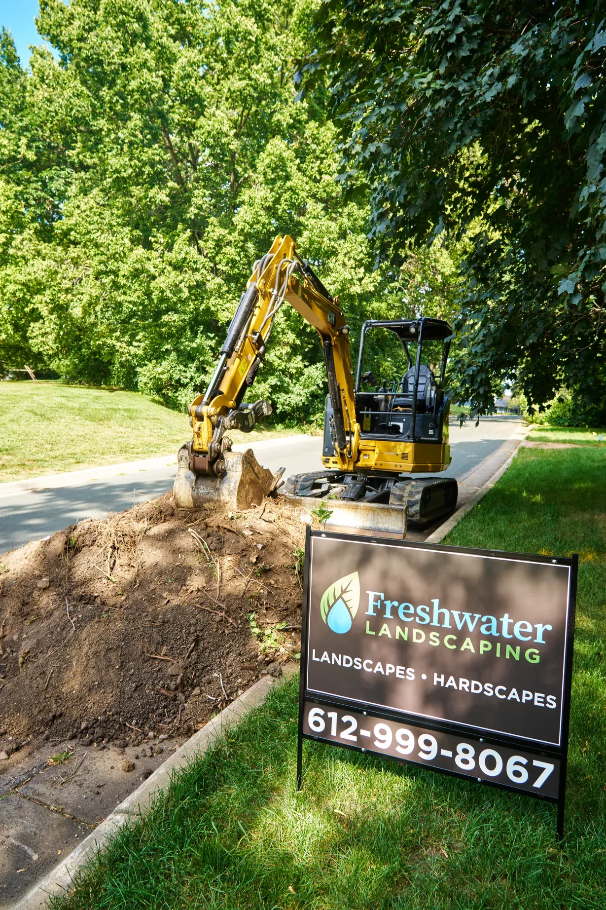 Freshwater excavator at the curb beside a Freshwater yard sign