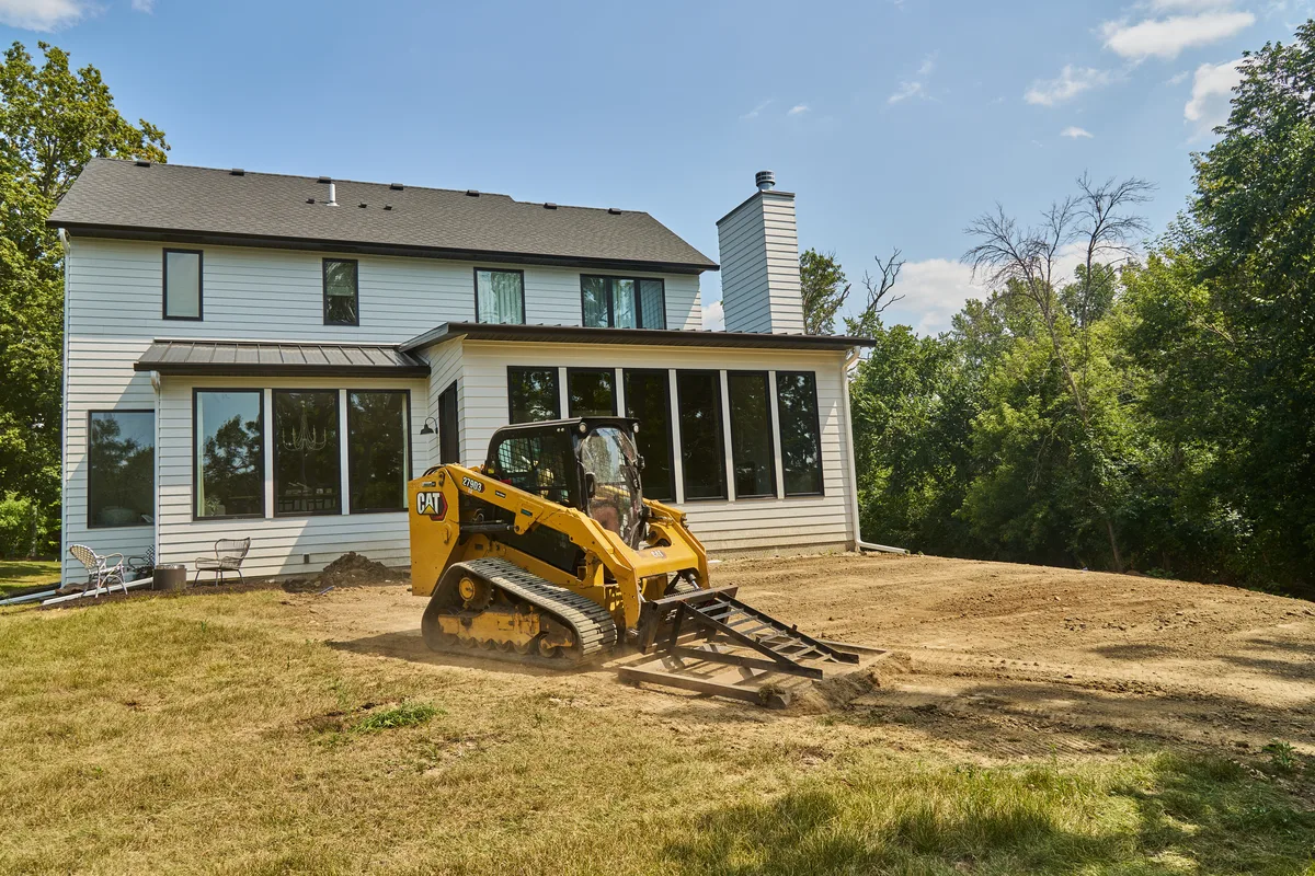 Skid steer grading a residential site before turf installation