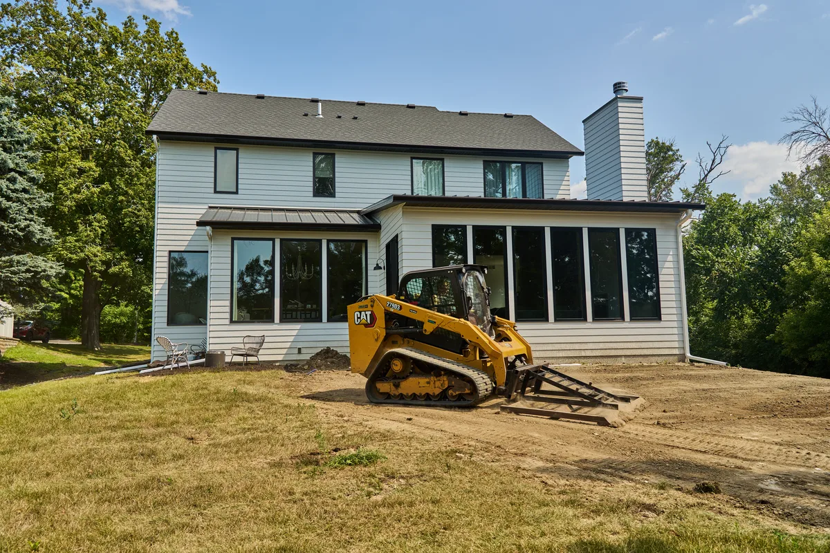 Skid steer grading a wooded residential lot in the Lake Minnetonka area
