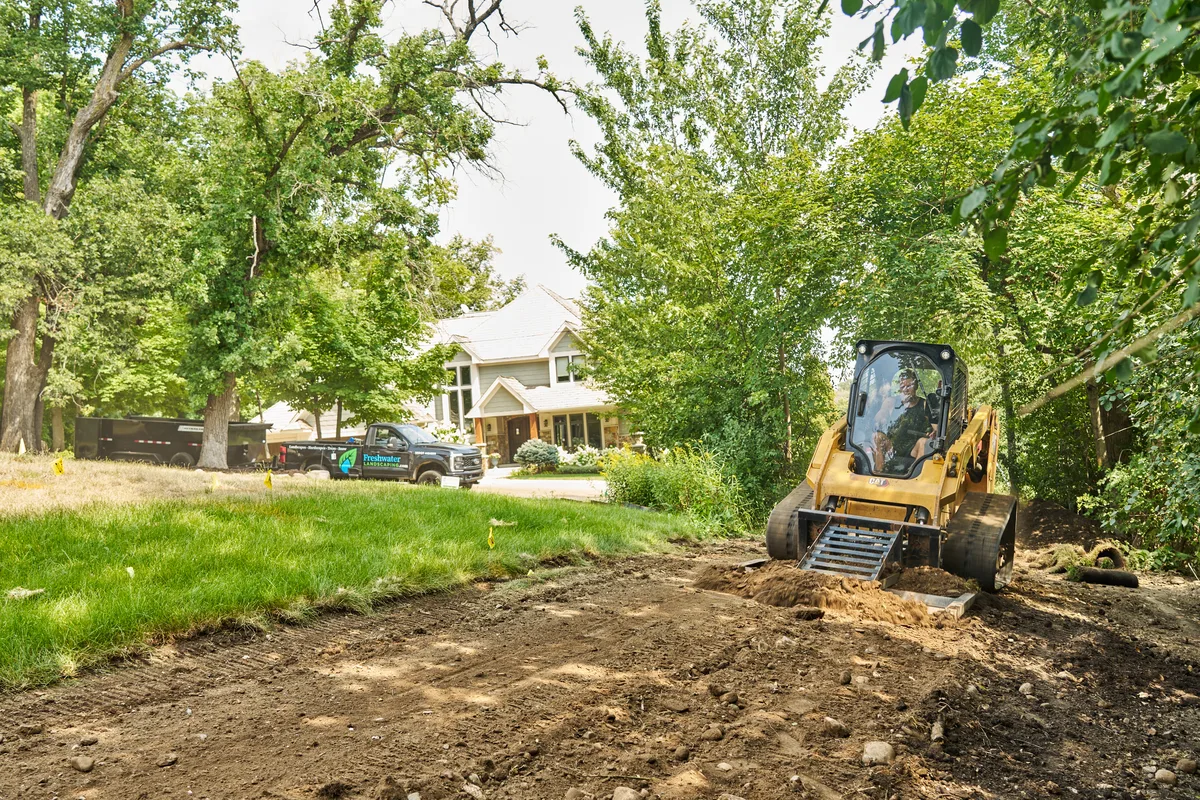 Skid steer clearing spoil and old rock from a residential site