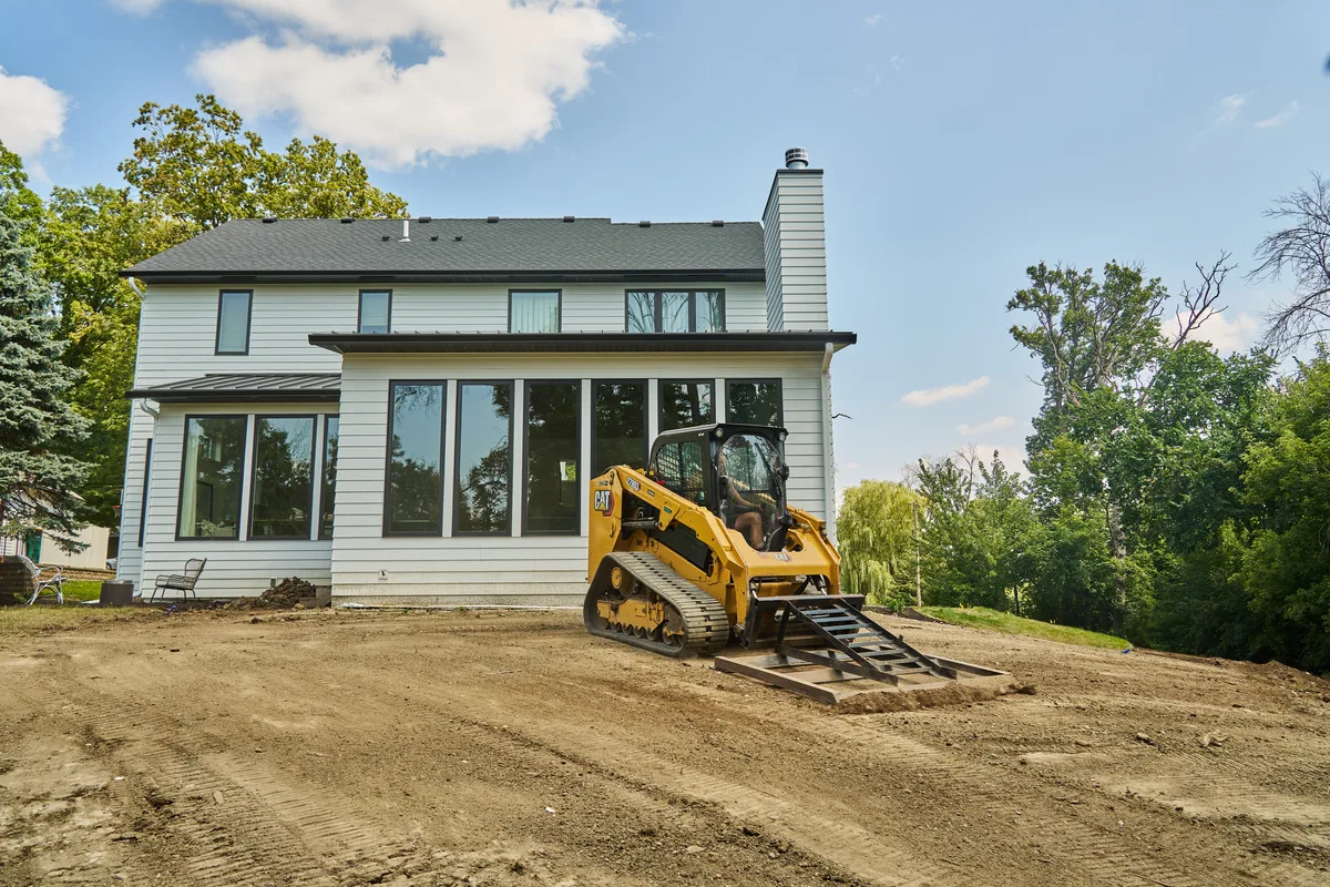 Skid steer grading a residential yard in Excelsior