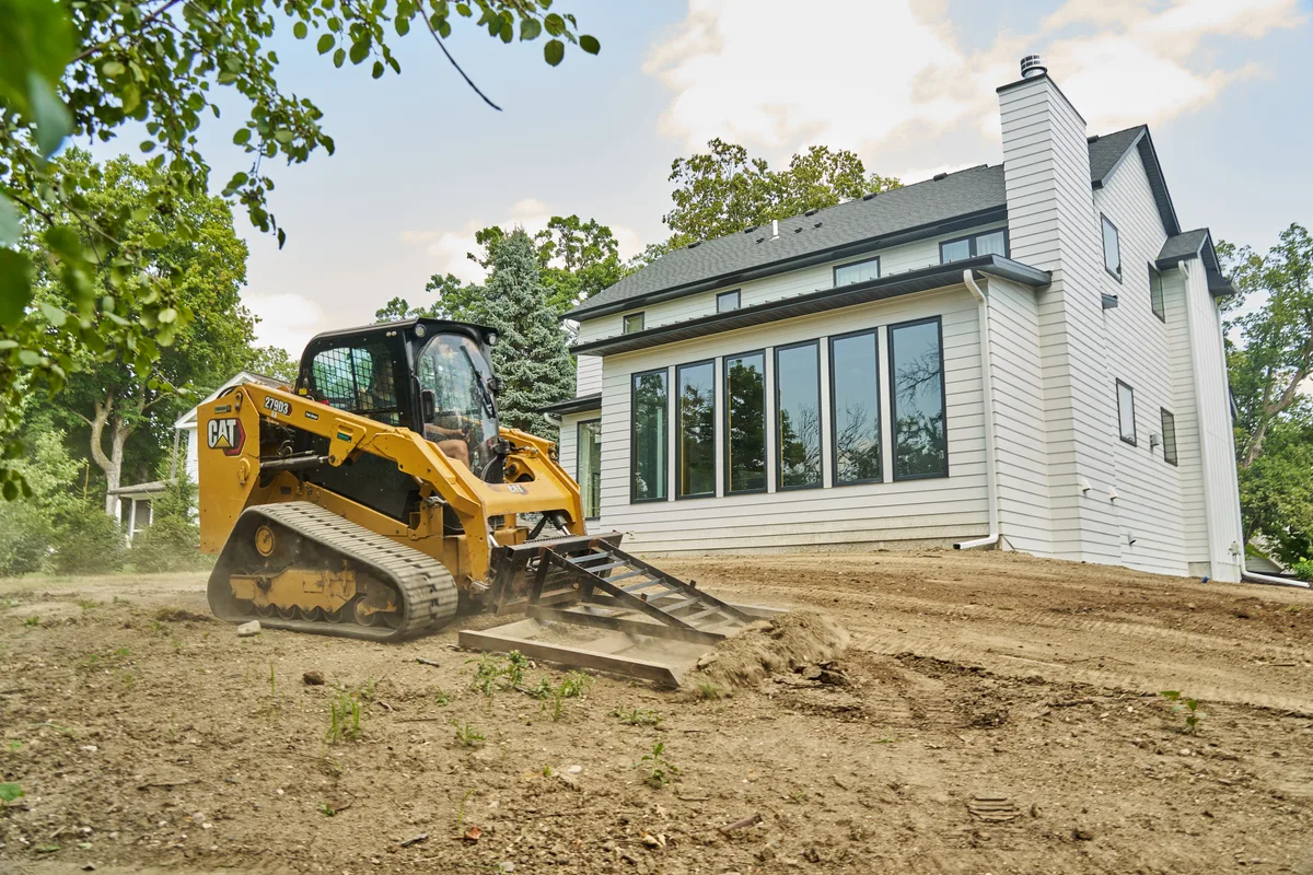 Skid steer grading a residential lot in Long Lake