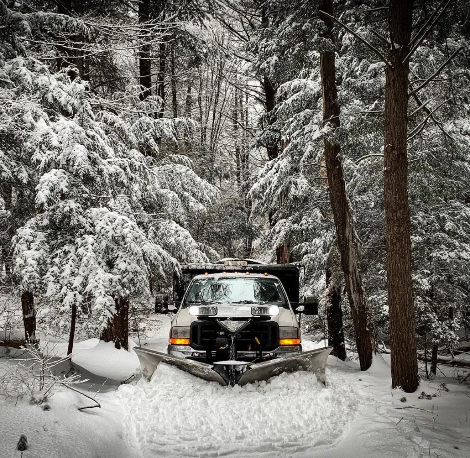 Plow truck clearing a residential driveway in Plymouth